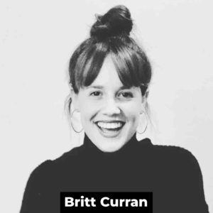 A black and white photo of a smiling white woman with medium dark hair with bangs and a bun on top of their head. They wear a black turtleneck. At the bottom of the photo are the words 'Britt Curran' in white bold text on a black rectangle.